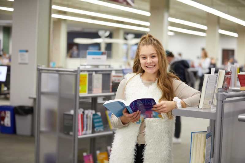 Student browsing the new book display in the library