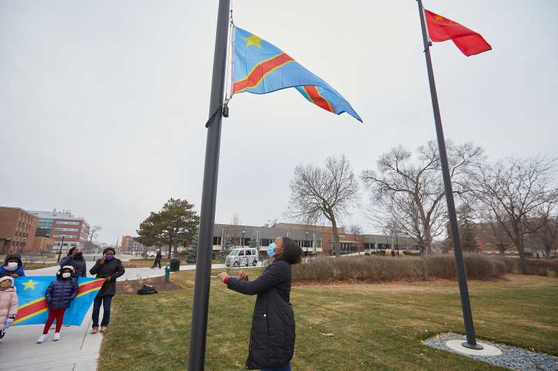 UWL Senior Vanessa Mbuyi Kaja raises the flag of the Democratic Republic of Congo for the first time on campus during a December 2020 ceremony. “I already knew I was accepted here in La Crosse, but this makes me feel like yes, I can call this my home,” noted the microbiology major.