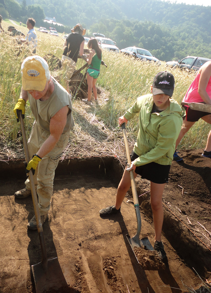 People shoveling at excavation site. 