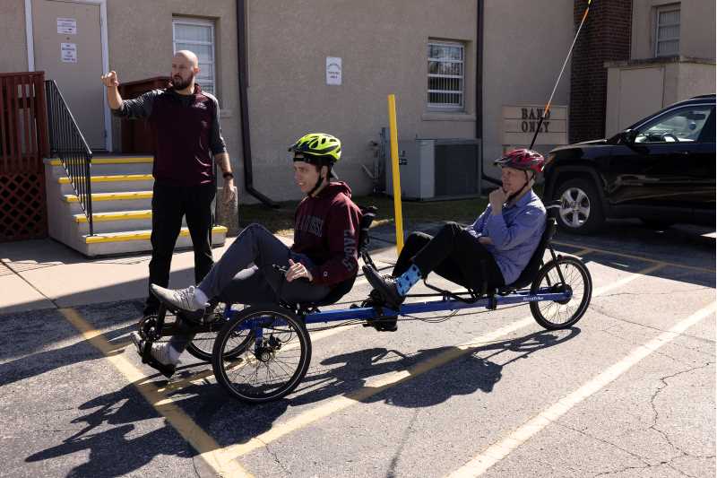 Assistant Professor Tommy Means, Recreation Management and Therapeutic Recreation Department, standing, leads a 400-level assessment class therapeutic recreation student in helping run an assessment clinic and bike fitting with community members in Can’t Stop Me Parkinson’s Program. The new terra trike recumbent bicycle is available for students and community members to rent through UWL’s Outdoor Connection.