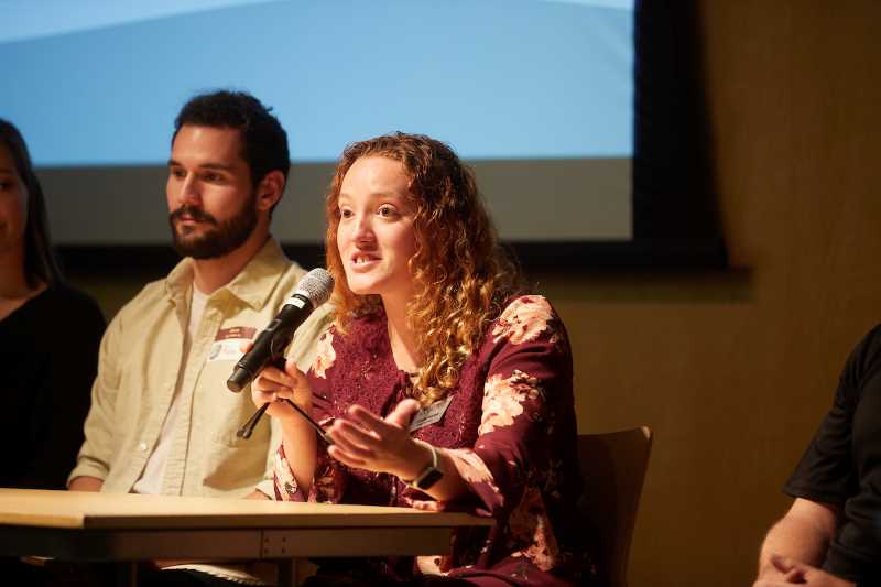 A graduate student speaks at a campus meeting