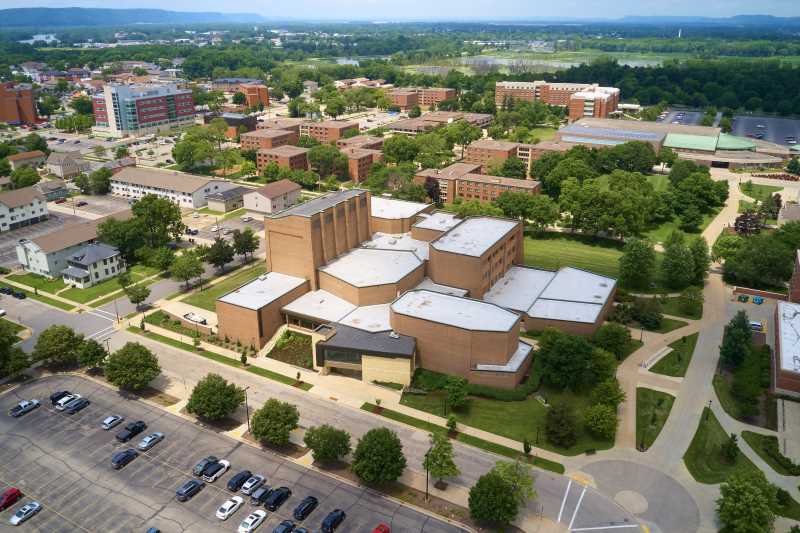 Summer aerial view of the UWL campus with the Center for the Arts building as the front focus and a view of the marsh and Minnesota bluffs in the background