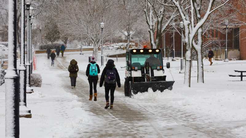 2019 photo of students walking on a campus sidewalk, recently cleared of snow.