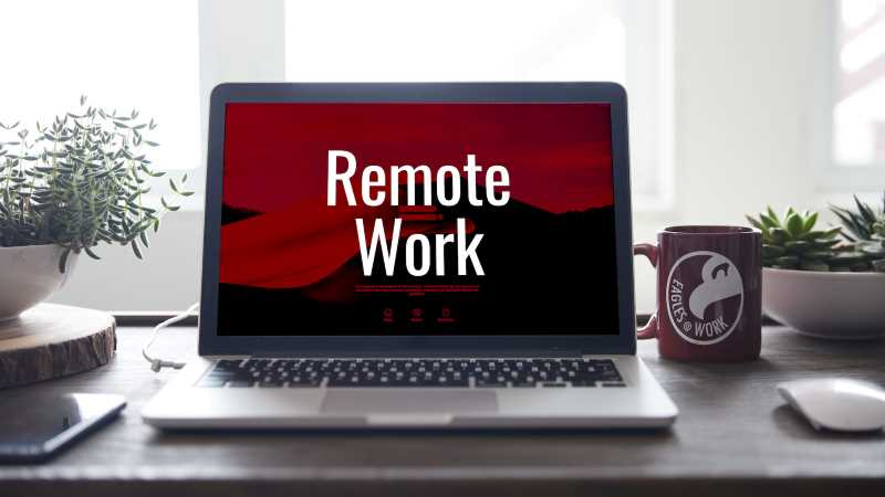 Laptop computer on a desk. Monitor has the words: remote work. 