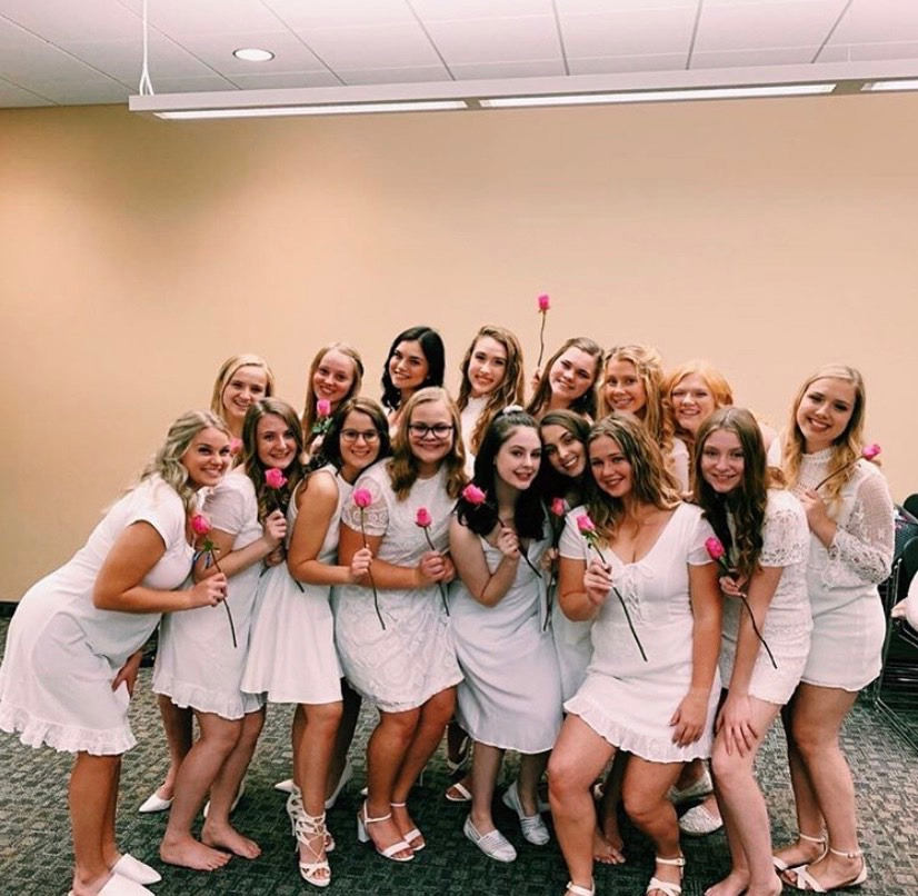 Alpha Xi Delta women wearing their white dresses pose for a photo after their initiation.