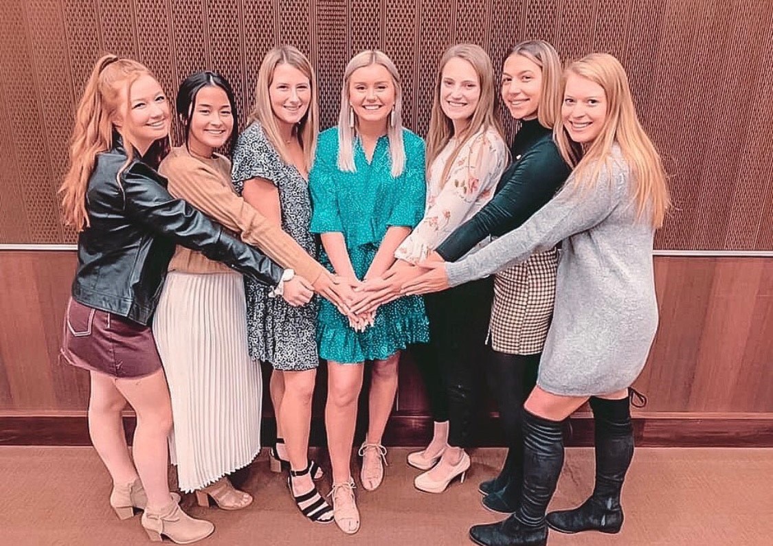A group of sorority women come together for a photo after an Alpha Phi meeting.
