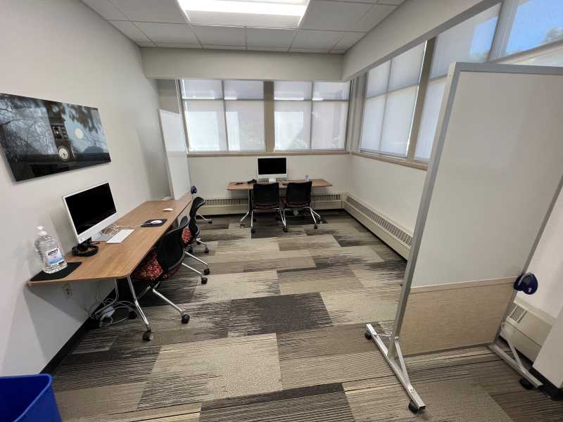 Seats 6. Space includes two portable white boards, two computer stations, and a desk for users with laptops.