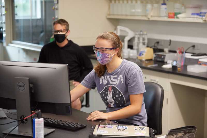 Students in lab setting wearing a facemask.