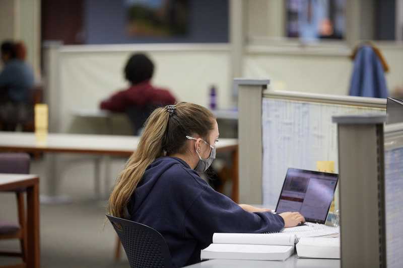 Student wearing mask studying in the library