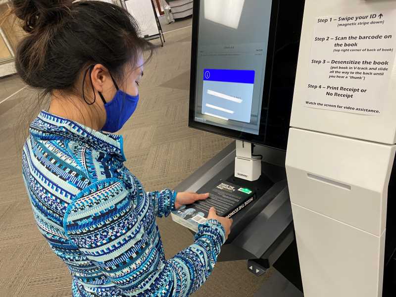 UWL student checking out a book at the self-checkout machine