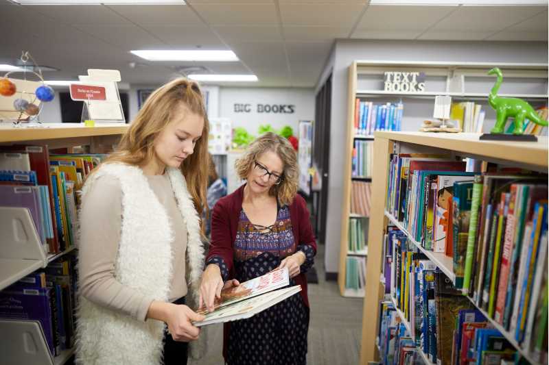 Engagement and Curriculum Collection Librarian Teri Holford helping a student locate a book in the Curriculum Center
