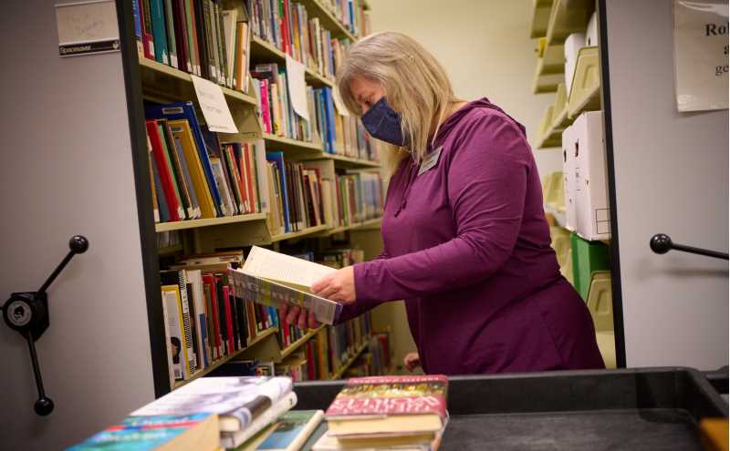 Collection Development Librarian Pam Cipkowski selecting books to donate to Afghan refugees