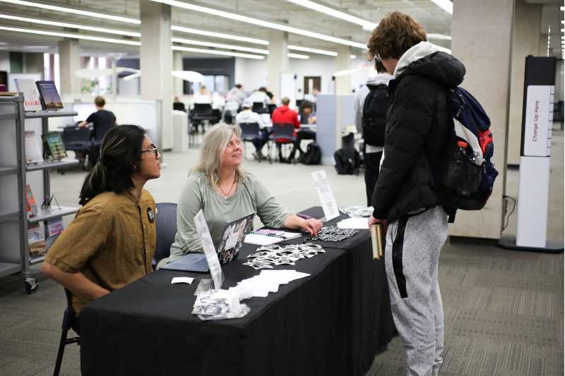Outreach Student Assistant Kang Duong and Collection Development Librarian Pam Cipkowski helping a UWL student sign up for the WSJ.com