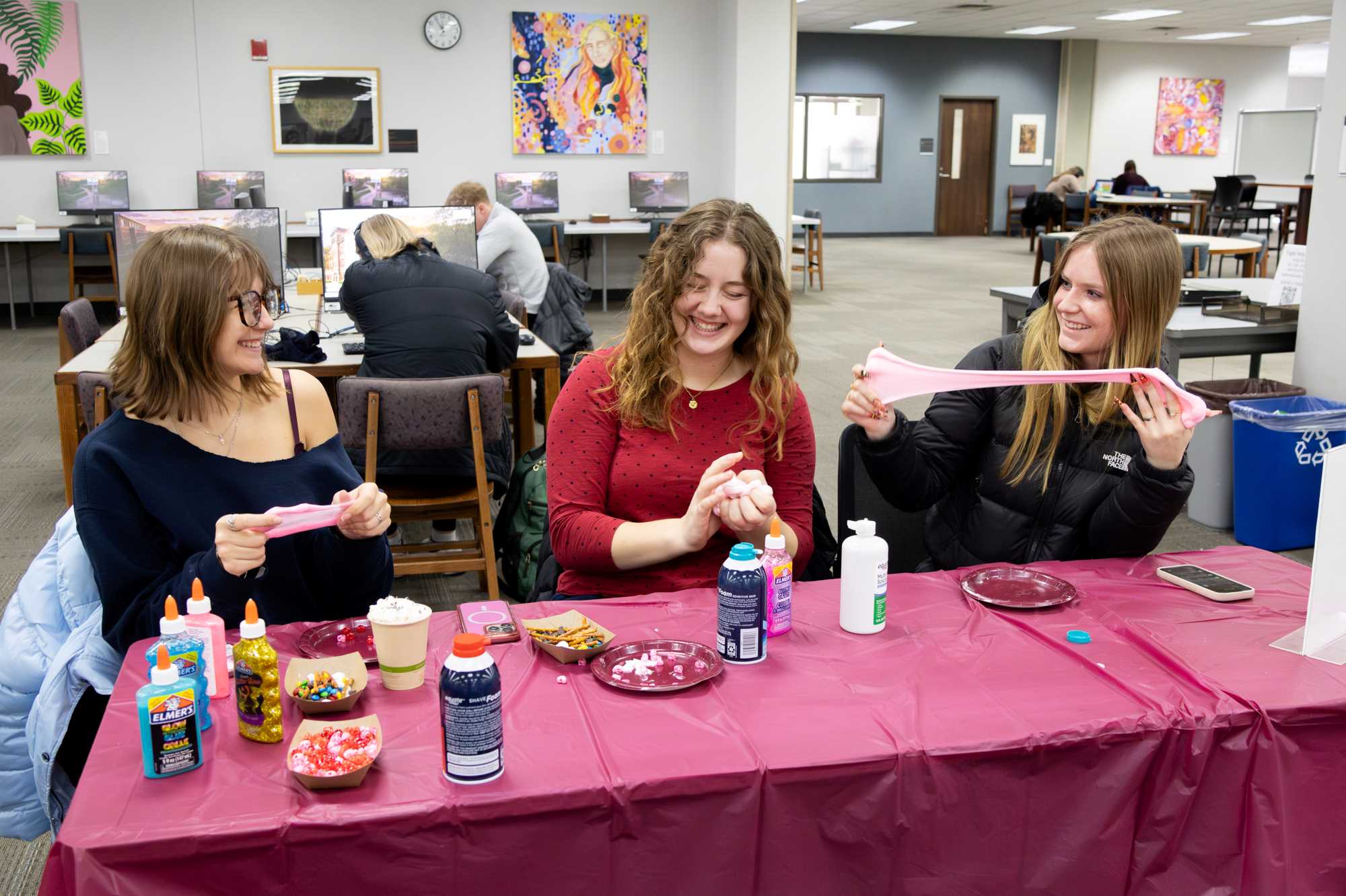 Alt text: Three students play with slime they made with UWL's Second Year Experience in Murphy Library.