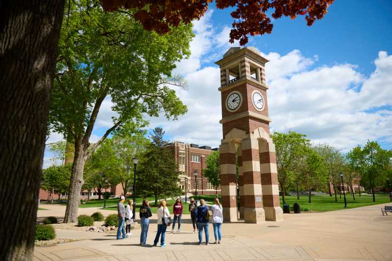 A group of prospective students and families tours the UW-La Crosse campus, stopping near the centrally located Hoeschler Tower.