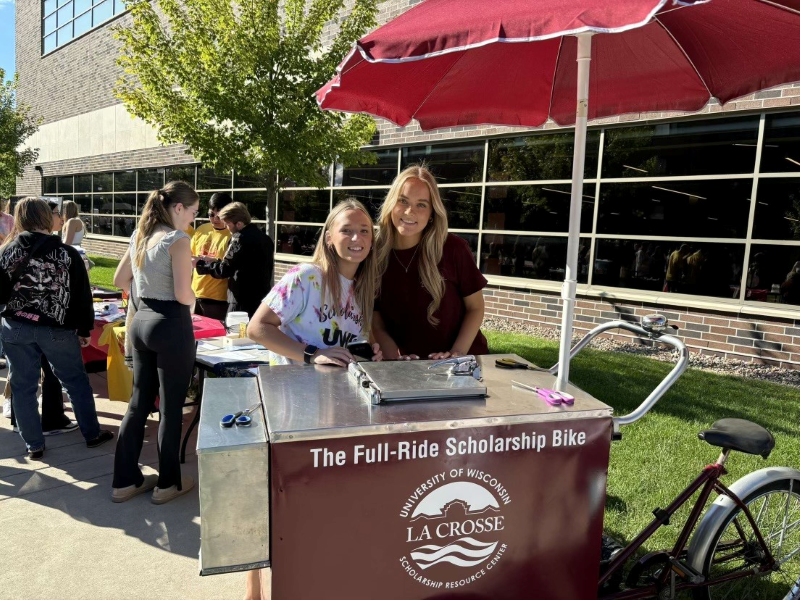 UWL students with the Full-Ride Scholarship Bike, one of the ways UWL financial aid counselors and peer advisors attract interest and teach about the importance of scholarships. 