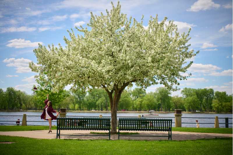 A graduate poses by a flowering crabapple tree in Riverside Park.