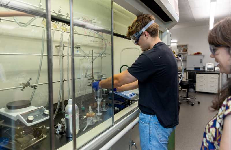 Roman Domashevsky, a junior majoring in biology with a biomedical concentration, was part of the Dean’s Distinguished Fellowship program this summer. He is pictured working with organic solvents under the fume hood in the Prairie Springs Science Center’s chemistry lab, alongside his faculty mentor,  Robin Grote.