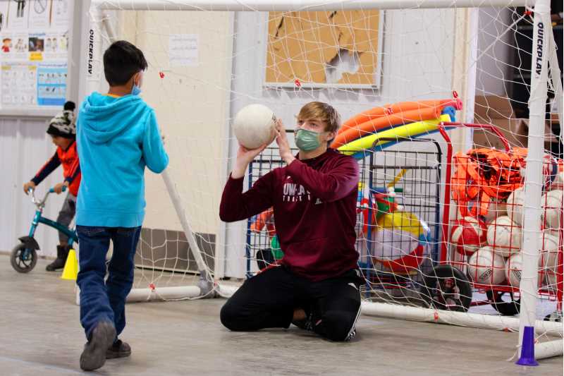 Spencer Reichart, a junior sprinter at UWL, tosses a ball to a child during the youth sports camps at Fort McCoy. The camps are intended to engage Afghan child evacuees while giving UWL students valuable experience working with children.