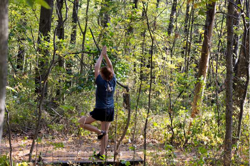 UWL student Paige Coleman does a yoga pose on a wooden structure that students in a recreation management course added for quiet time and meditation among the pines on the Hickory Trail. This designated area for forest therapy is less than 1 mile into the woods on the Hixon Forest trail.