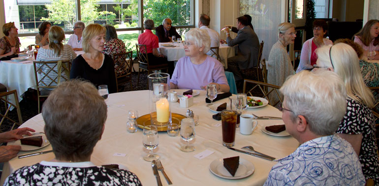 Women eating with speaker at far table. 