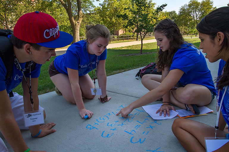 Students doing math problem on sidewalk.