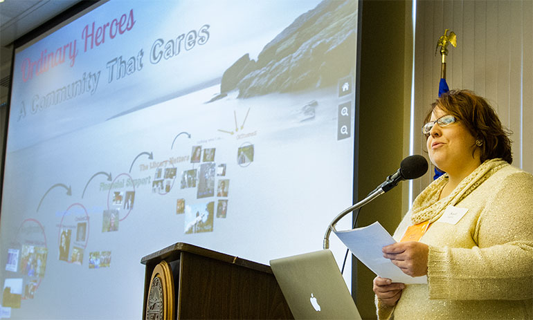 20121107__SSP_Breakfast_2012_0057we Susan Fabian at podium with photo displayed.