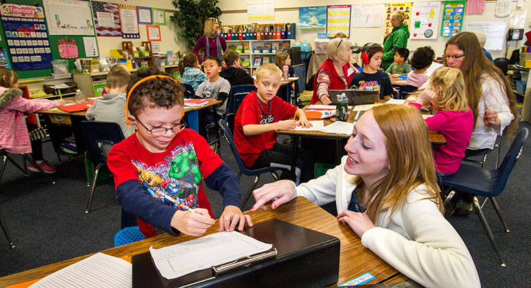 College student with students in classroom. 