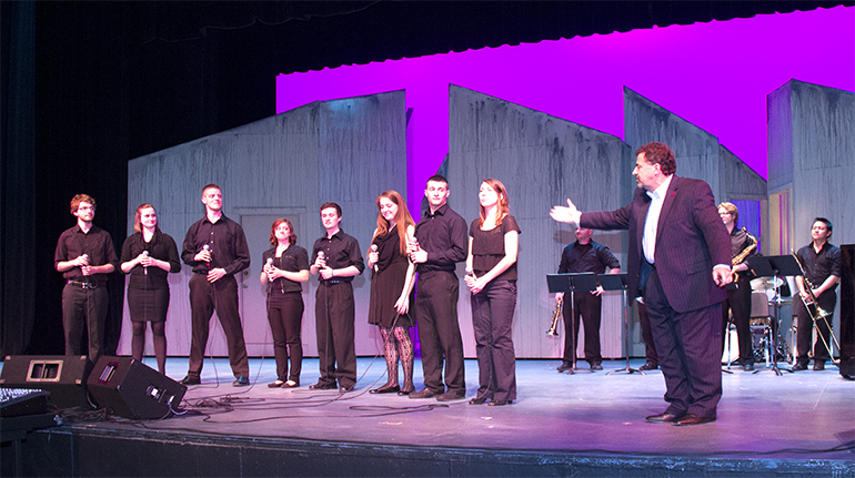 Image of students performing on a stage with Professor Gary Walth in the foreground. 