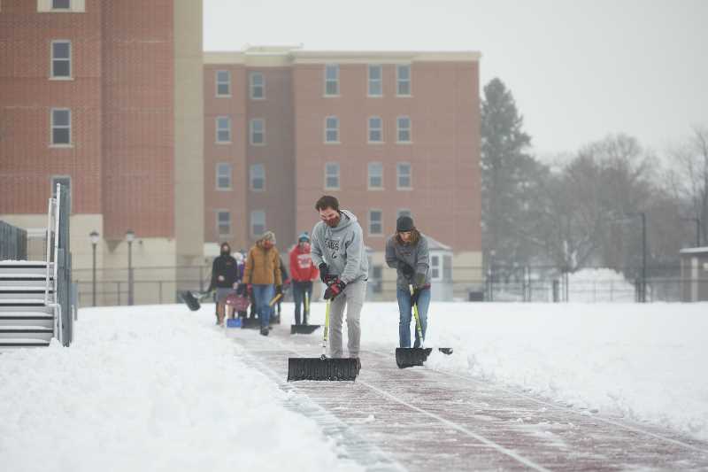 Student athletes from the Cross Country team shovel a few track lanes after a recent snow.