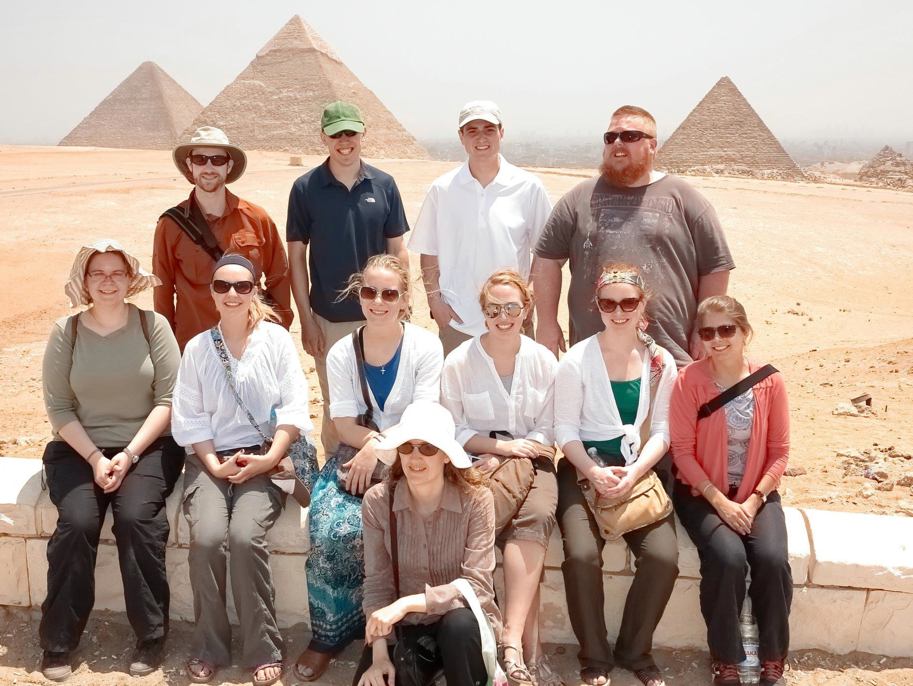 Assistant Professor Heidi Morrison stands with group of students in front of Egyptian pyramids.