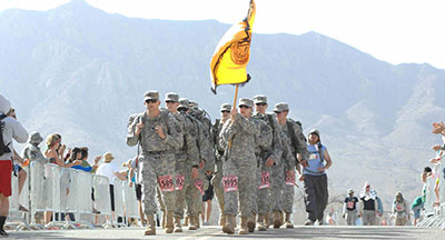 Soldiers marching with flag at finish line.