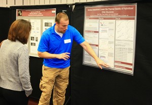 UW-L student Tyler Petty pointing to information on his poster during the poster session portion of the event. 
