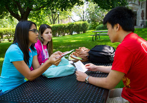 Students from Brazil talk with another international student at a pinic table outside Wittich Hall. 