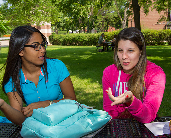 Two students from Brazil discuss at picnic table outside at UW-L. 