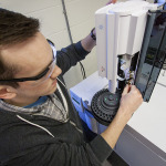 Image of Brian Peterson working with a piece of equipment that anaylzes products after a chemical reaction.