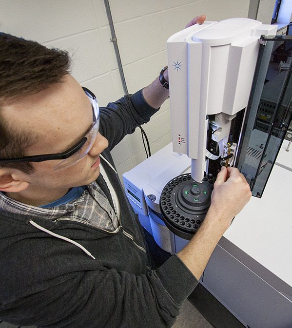 Image of Brian Peterson working with a piece of equipment that anaylzes products after a chemical reaction.