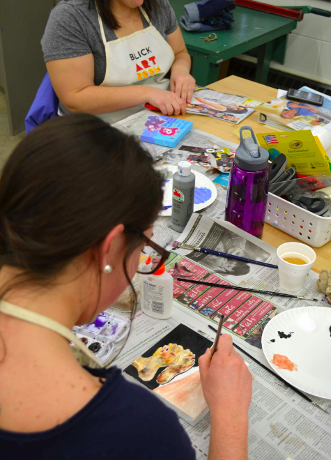 Students working painting at a table.