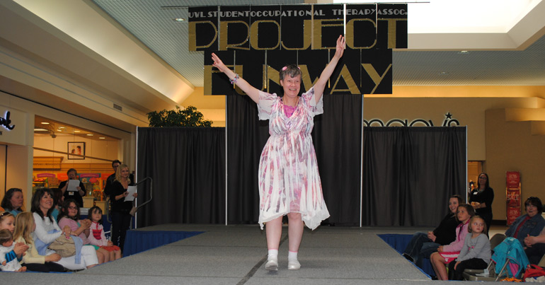 Woman on stage modeling clothes.