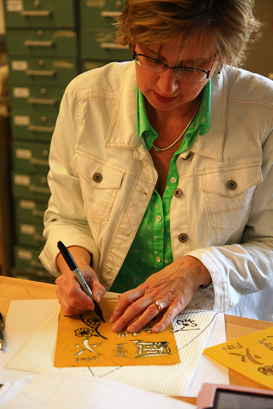 Woman tracing an object on a piece of paper.