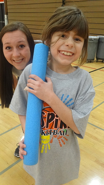 Image of a student standing behind a child. 