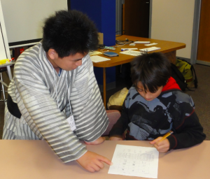 Image of Takumi Tamura teaching Japanese calligraphy to a Logan Middle School student