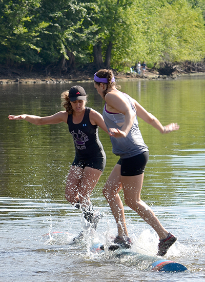 Two peole rolling on a log. 