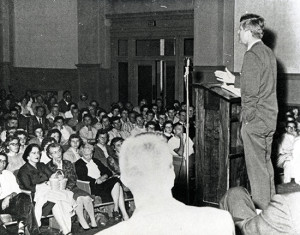 Image of John Kennedy speaking in Graff Main Hall auditorium. 