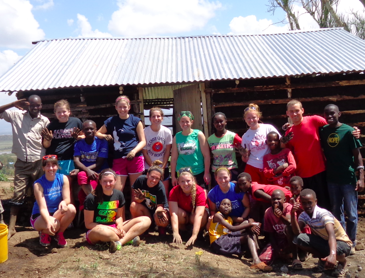 Image of UW-L students from Kenya Make a Difference stand in front of a house they helped build for a family in need in Kenya. 