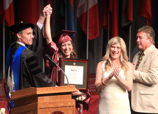 Image of Kim Graham with her parents standing alongside her and UW-L Chancellor Joe Gow holding her hand and raising it in the air. 