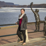 Catherine Krus stands next to simpler time sculpture at Riverside Park, overlooking the Mississippi River.