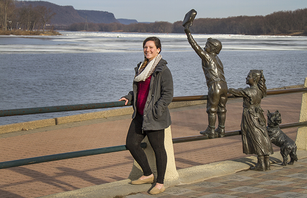 Catherine Krus stands next to simpler time sculpture at Riverside Park, overlooking the Mississippi River.