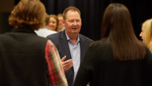 Image of Joe Laux talking in a crowd of people.