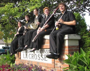 Four musicians sitting on UW-L sign.